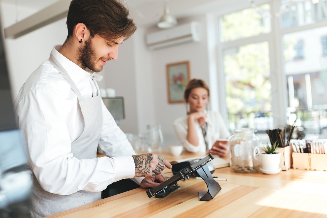 Uśmiechnięty barista przy kasie w kawiarni